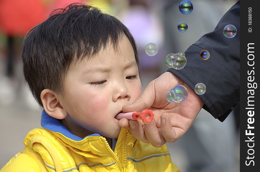 A child blowing soap bubbles in a park. A child blowing soap bubbles in a park