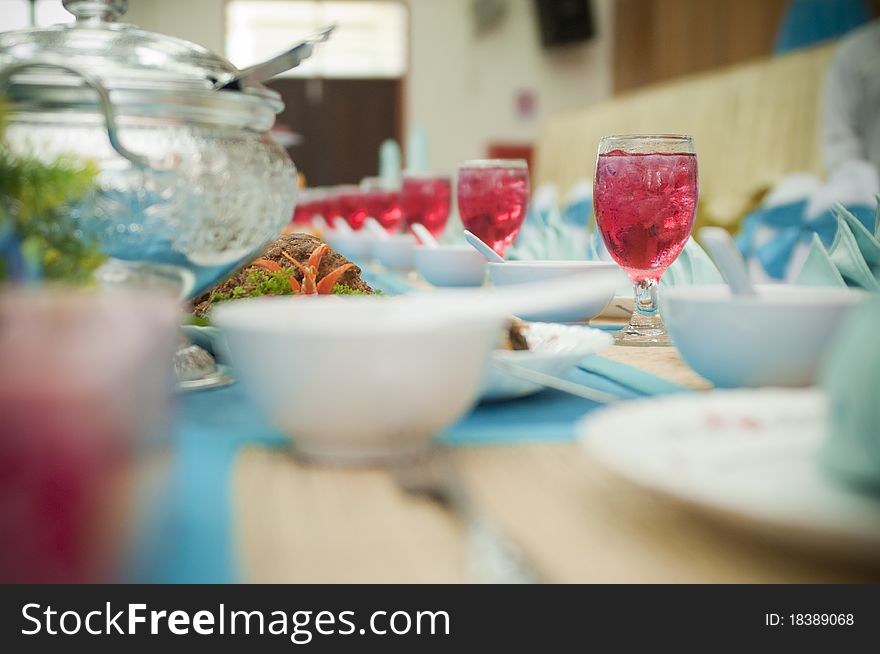 A row of glasses filled with water arranged in a row on a dining table with bokeh effect. A row of glasses filled with water arranged in a row on a dining table with bokeh effect