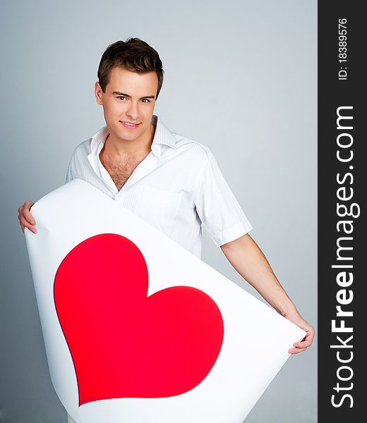 Handsome young man holding a red heart