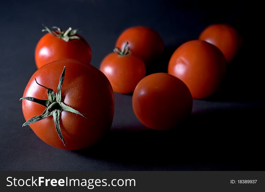 Photo from a couple of red tomatos, dark background.