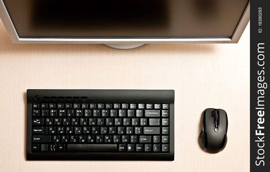 Black keyboard, mouse and monitor on a wood desk. Black keyboard, mouse and monitor on a wood desk.