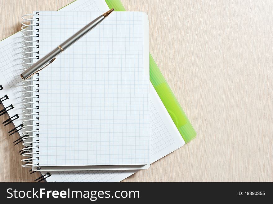 Blank spiral note pad with silver pen on wood desk. Blank spiral note pad with silver pen on wood desk