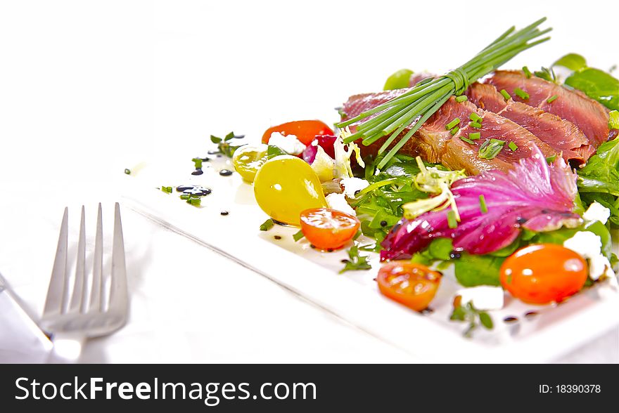 A prime cut of grilled, tender fillet beef on a healthy, and colourful herb salad. A prime cut of grilled, tender fillet beef on a healthy, and colourful herb salad.