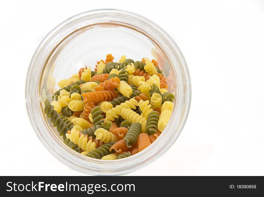Colorful raw fusilli in a glass jar on a white background. Colorful raw fusilli in a glass jar on a white background