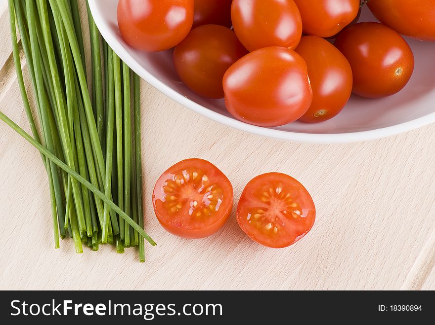 Fresh cherry tomatoes and chives on cutting board