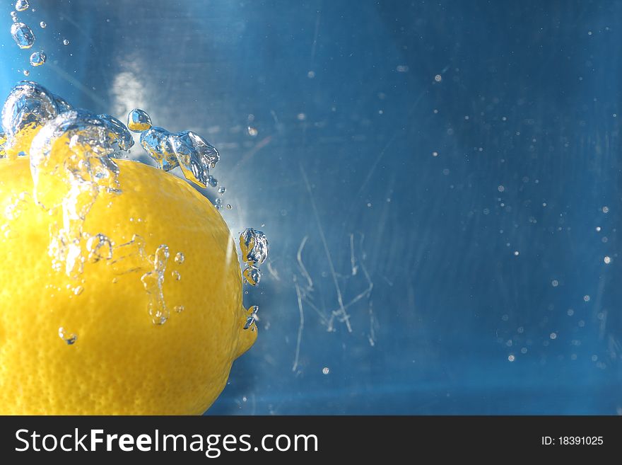 A yellow zesty lemon fully submerged in water.