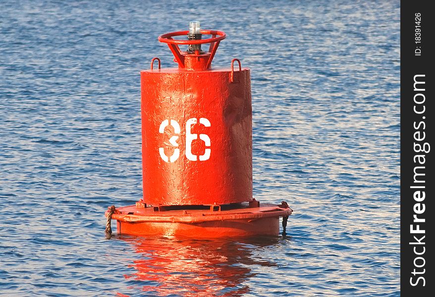 Red buoy with a lamp on the blue water (closeup). Red buoy with a lamp on the blue water (closeup).