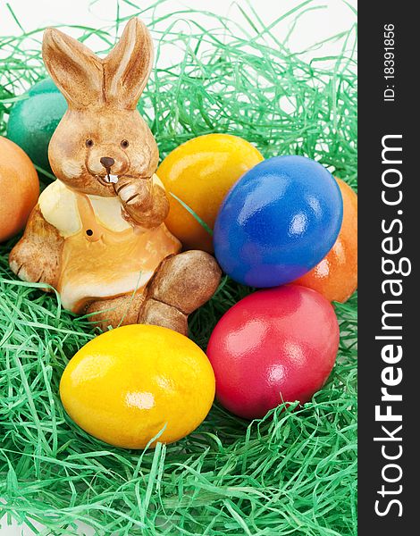 Easter bunny sitting in a nest with colored eggs