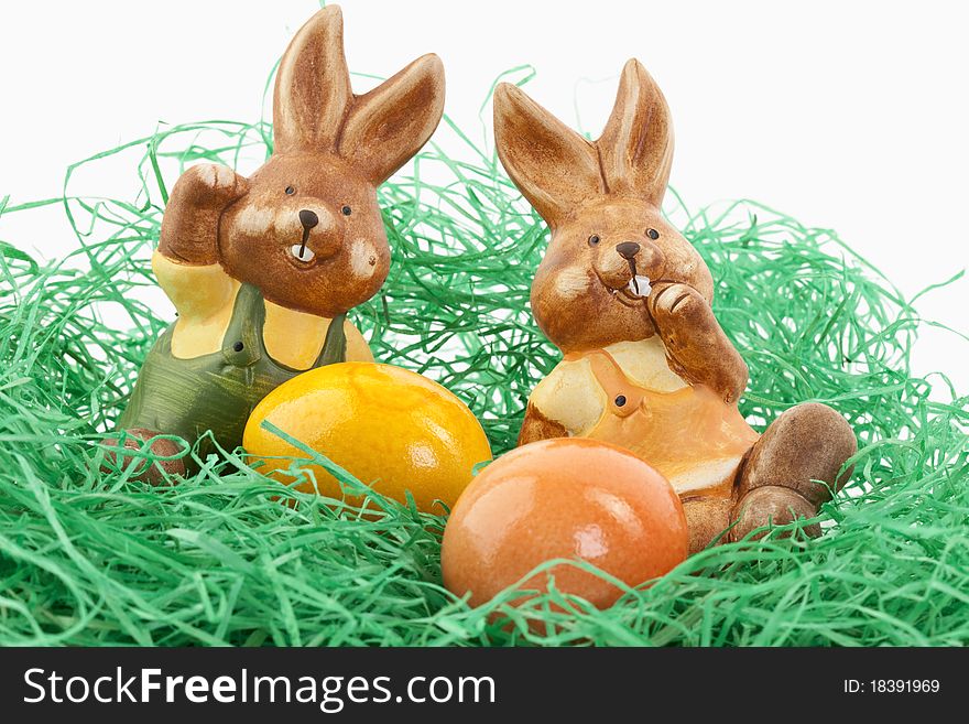 Two easter bunnies sitting in a nest with colored eggs. Two easter bunnies sitting in a nest with colored eggs