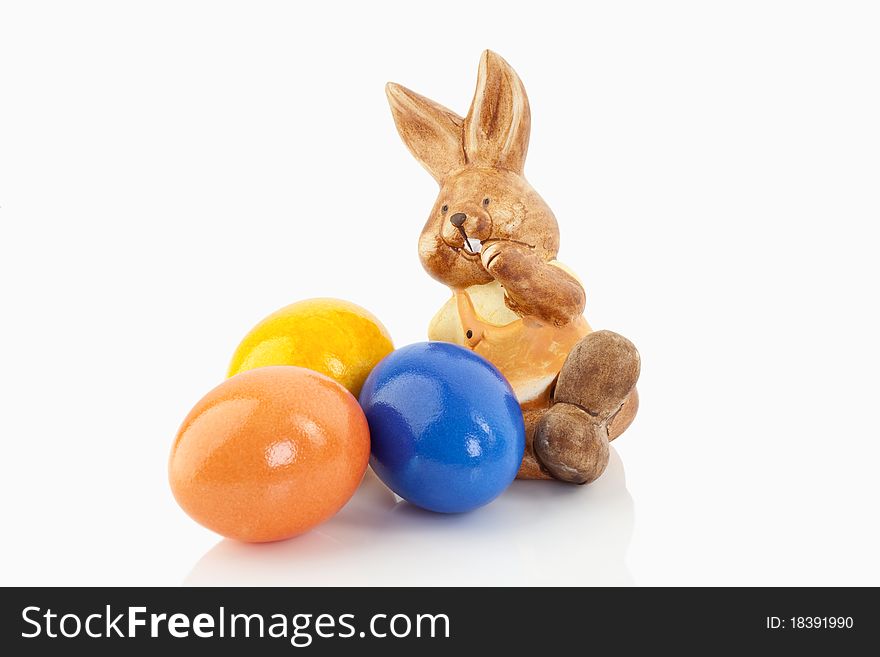 Easter bunny sitting on a white background close to colored eggs on