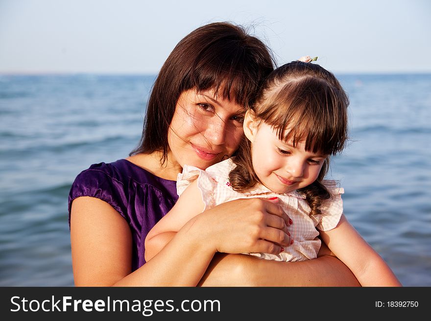 Mother hugging her daughter on sea background. Mother hugging her daughter on sea background