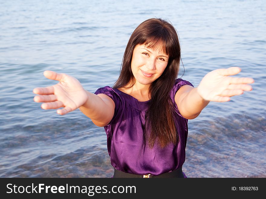 Beautiful young woman opened her hands with delight at the blue sky