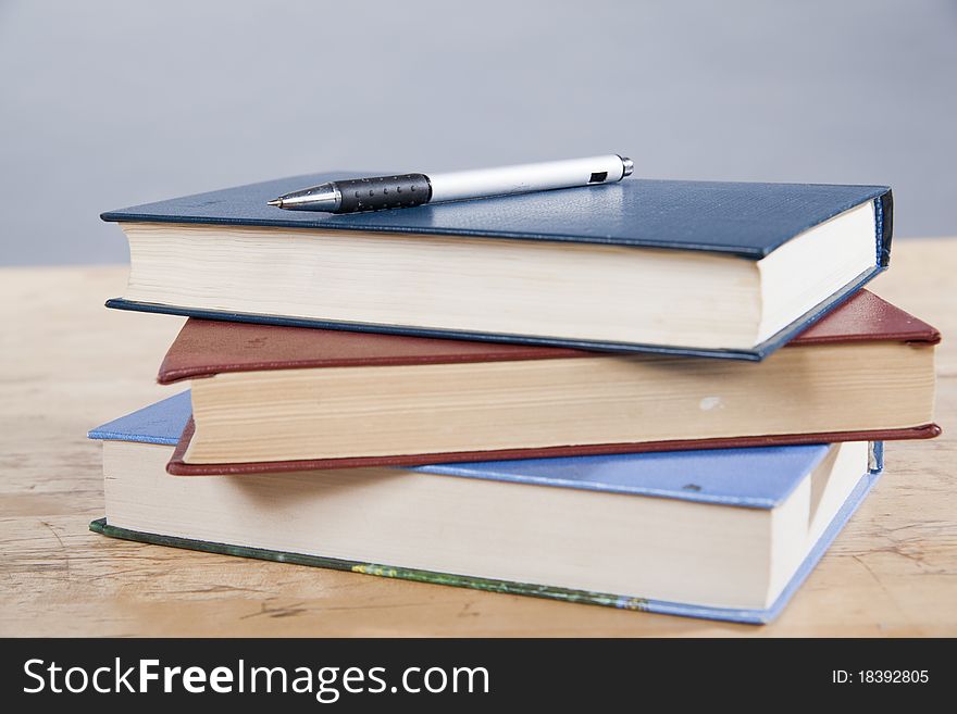 Pen lying on a pile of three books. Pen lying on a pile of three books