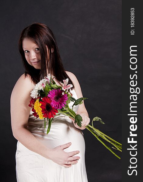 Pregnant Woman In White Dress With Gerbera Bouquet