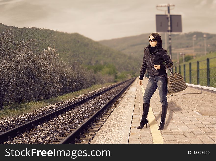 Photo of young woman waiting at the train station for its train. Photo of young woman waiting at the train station for its train