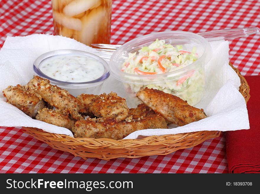 Chicken strips meal with coleslaw and sauce in a basket