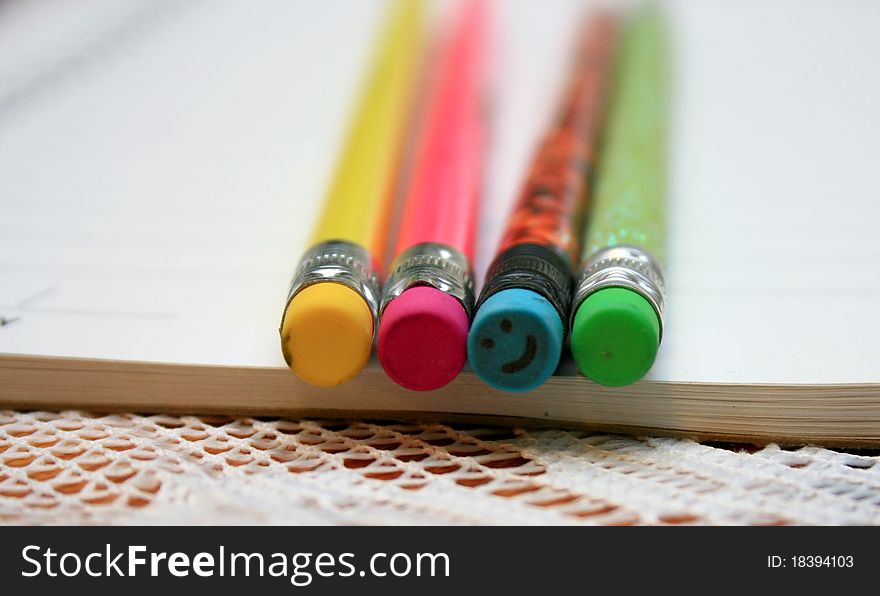 Four bright colored pencil erasers, with one smiling back.