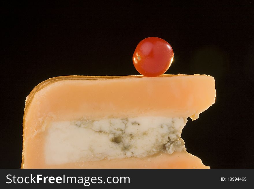 Gloucester cheese with Cheese blue slice on a black background with tomato. Gloucester cheese with Cheese blue slice on a black background with tomato.