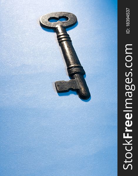 A metal key laying on a blue background. Add your text to the background.
