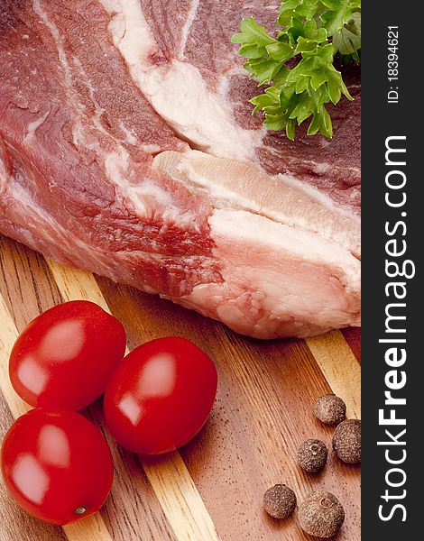 A piece of raw meat on a multilayer wooden kitchen cutting board.