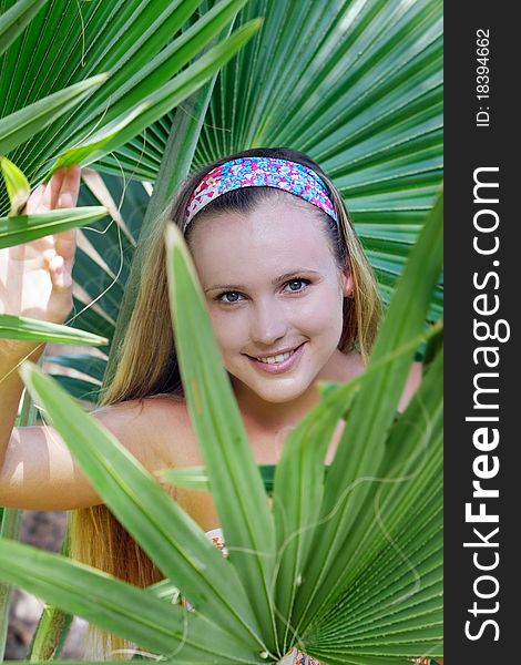 Young beautful woman looking through palm tree leaves. Young beautful woman looking through palm tree leaves