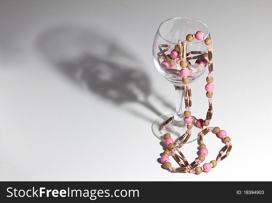 Bijoux necklace in vine glass, with dramatic shadow