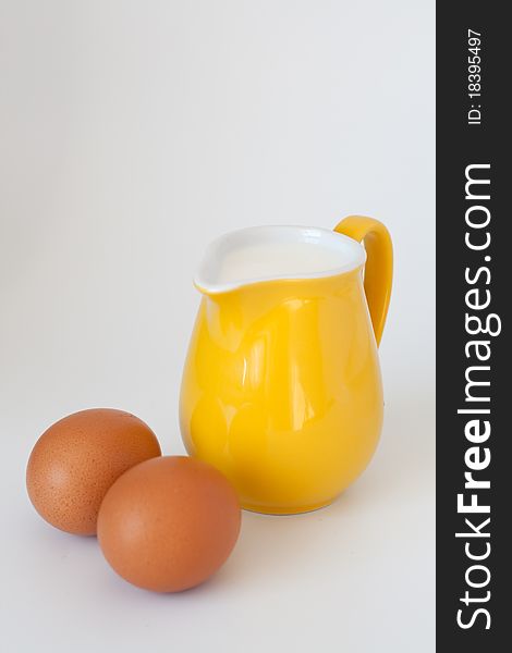 Pitcher of milk, eggs and flour on a white background