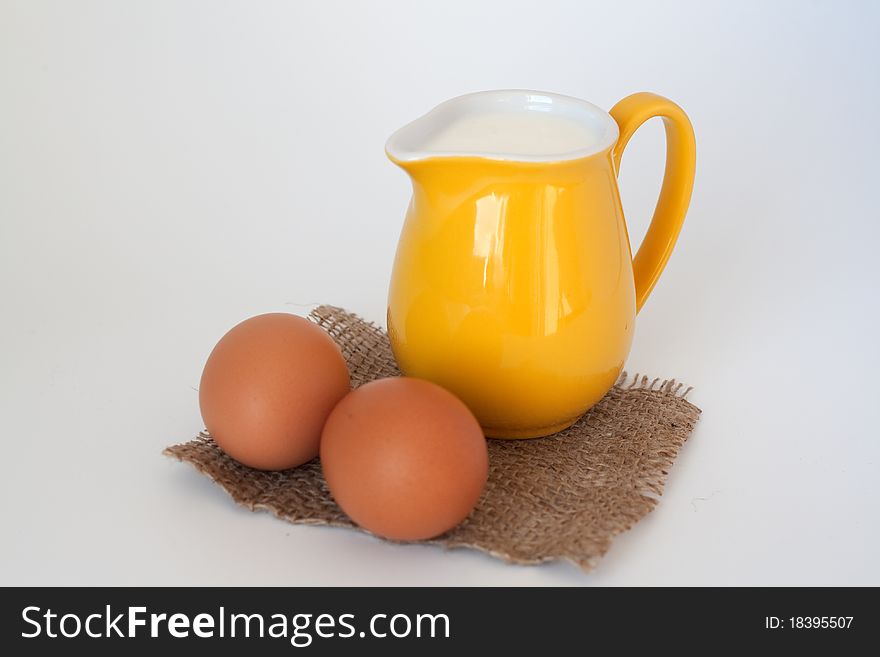 Pitcher of milk and eggs on a white background