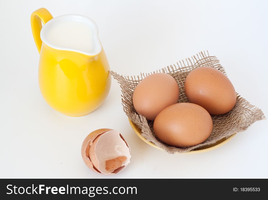 Pitcher of milk and eggs on a white background