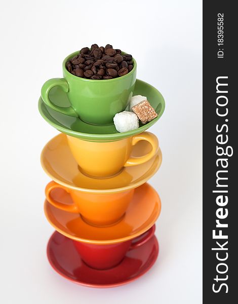 Four colorful cups with sugar and coffee beans are on a white background. Four colorful cups with sugar and coffee beans are on a white background