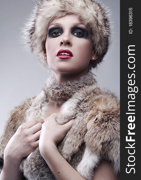 Beautiful young blond woman in fur, studio shot