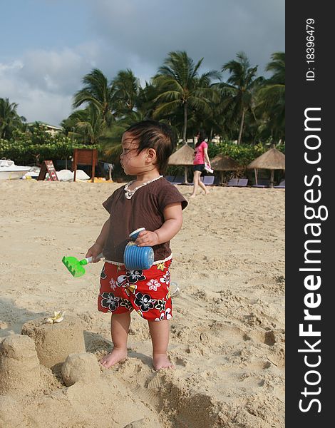 A little child holding the toys and playing on the beach