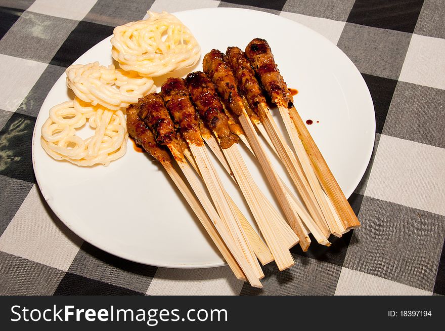 A traditional Balinese seafood skewers with crackers.