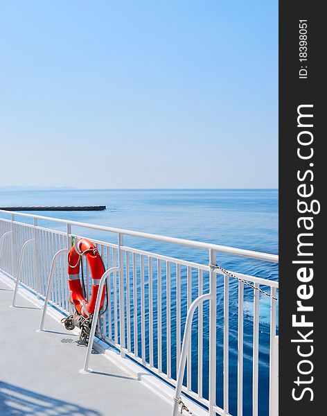 Red Lifebuoy in front of the blue sea and the white ship