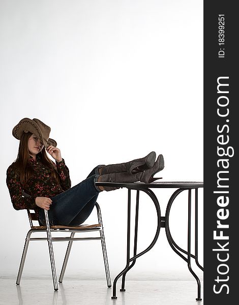 Attractive cowgirl with legs on table