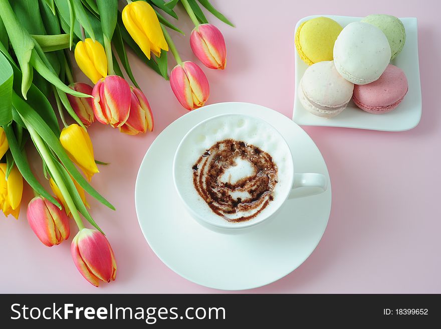 Cappuccino, macaroons and tulips on a pink background