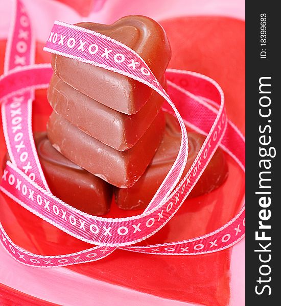 Stack of heart shaped chocolates wrapped with xoxoxo ribbon on a plate to be used for Valentine's Day or anniversaries, or romance. Stack of heart shaped chocolates wrapped with xoxoxo ribbon on a plate to be used for Valentine's Day or anniversaries, or romance