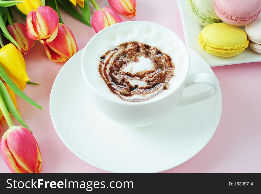 Cappuccino, macaroons and tulips on a pink background