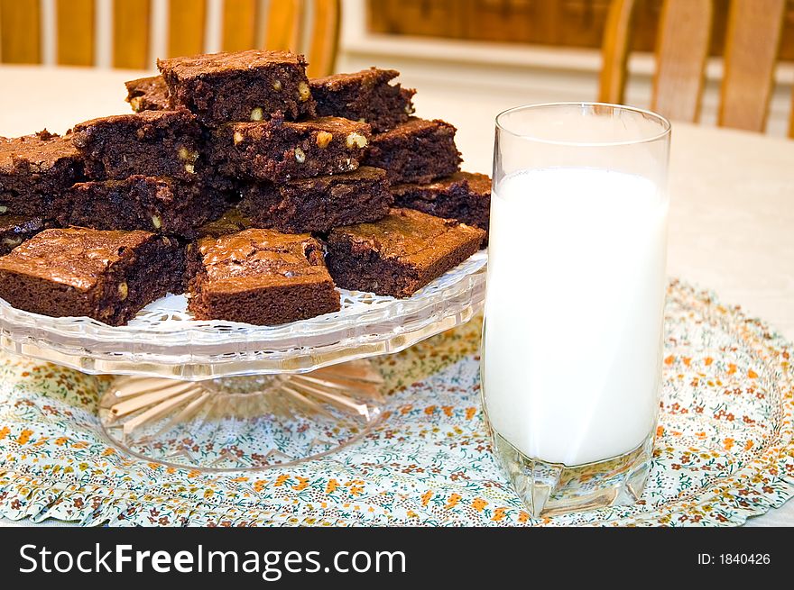 A plate of still-warm, fresh baked, homemade chocolate brownies with lots of walnuts and a glass of cold milk!. A plate of still-warm, fresh baked, homemade chocolate brownies with lots of walnuts and a glass of cold milk!