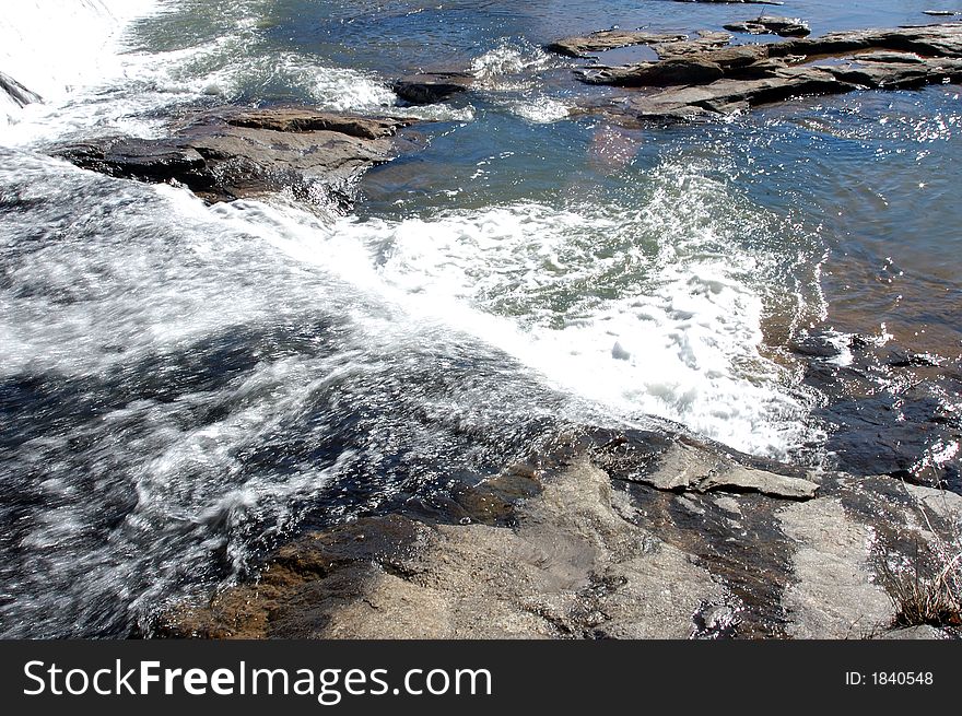 Water running over a dam and over boulders. Water running over a dam and over boulders