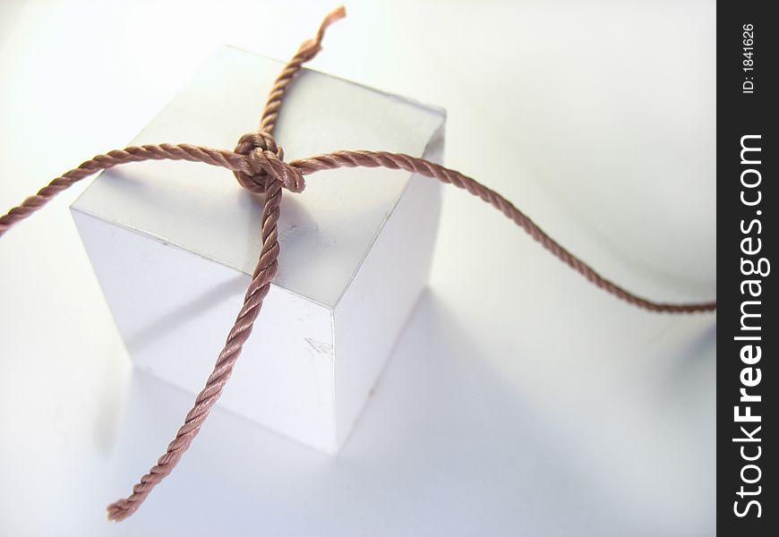 The fastened cord laying on a cardboard cube. The fastened cord laying on a cardboard cube.