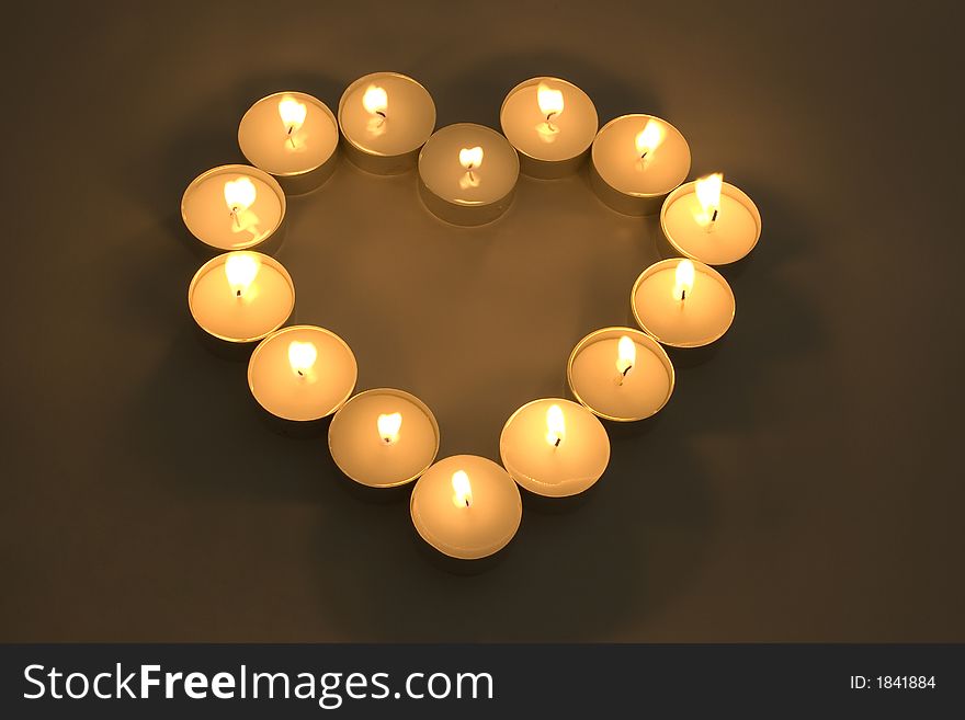 Group of burning candles placed in form of heart.