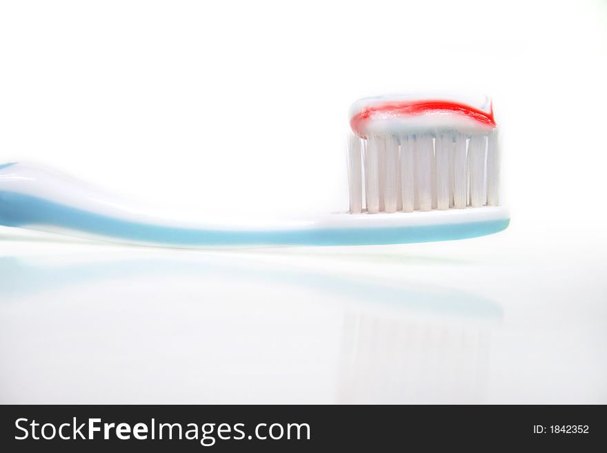 A toothbrush with toothpaste in front of white background