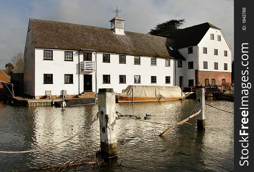 Winter scene of a an Historic Riverside Mill House with Boats moored to the front