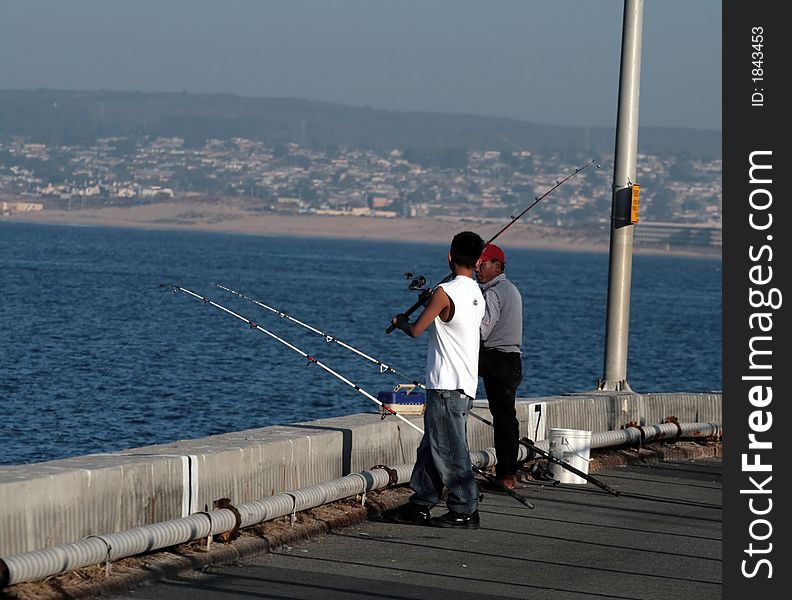 Fishermen fishing off a pier into the Pacific Ocean