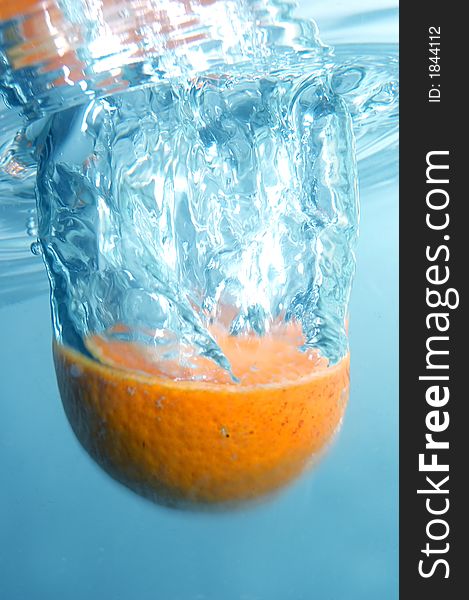 Fresh orange into blue, clear water