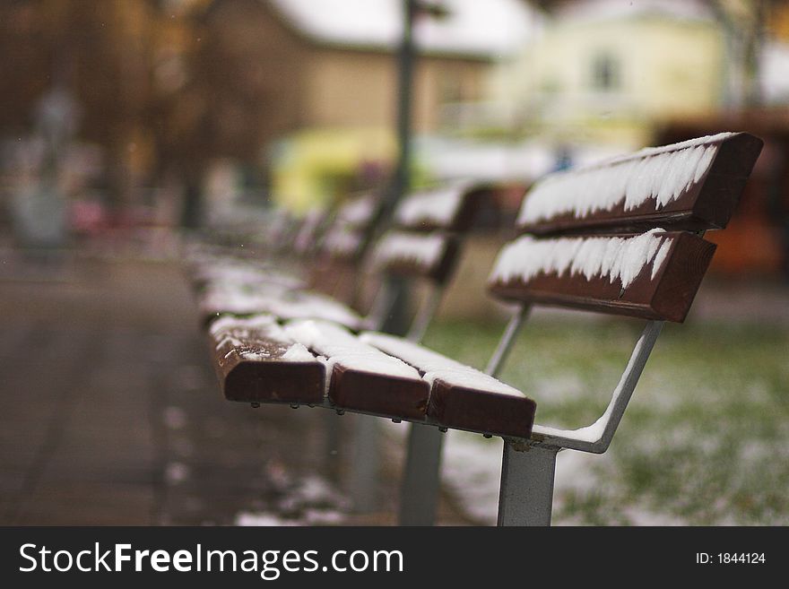 Abandoned benches in park. winter scene with snow. very shallow depth of field (F / 1.8). space for text. Abandoned benches in park. winter scene with snow. very shallow depth of field (F / 1.8). space for text