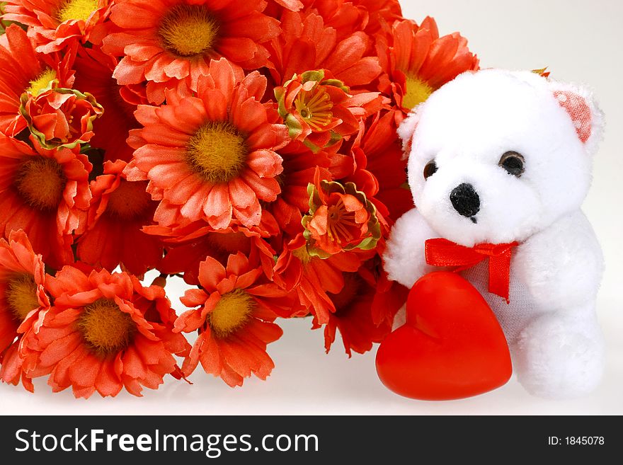 Teddy bear with heart and man-made flowers isolated on background. Teddy bear with heart and man-made flowers isolated on background