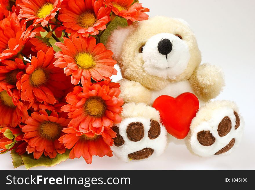 Teddy bear with heart and man-made flowers isolated on background. Teddy bear with heart and man-made flowers isolated on background