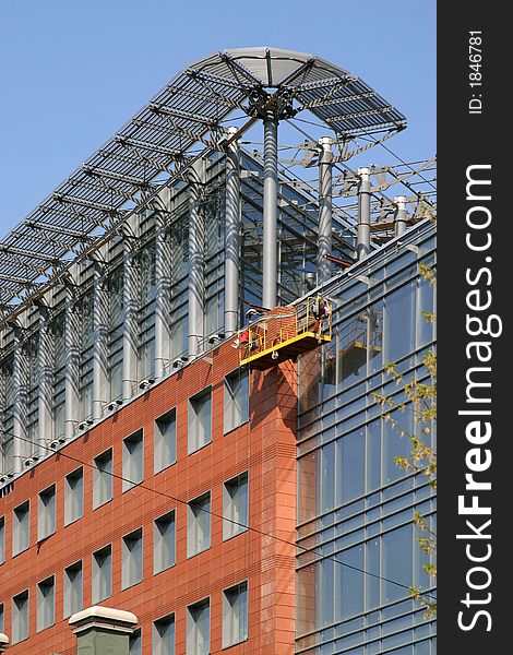 The closing stage of construction the business center, a building from glass and metal on a background of the blue sky. The closing stage of construction the business center, a building from glass and metal on a background of the blue sky